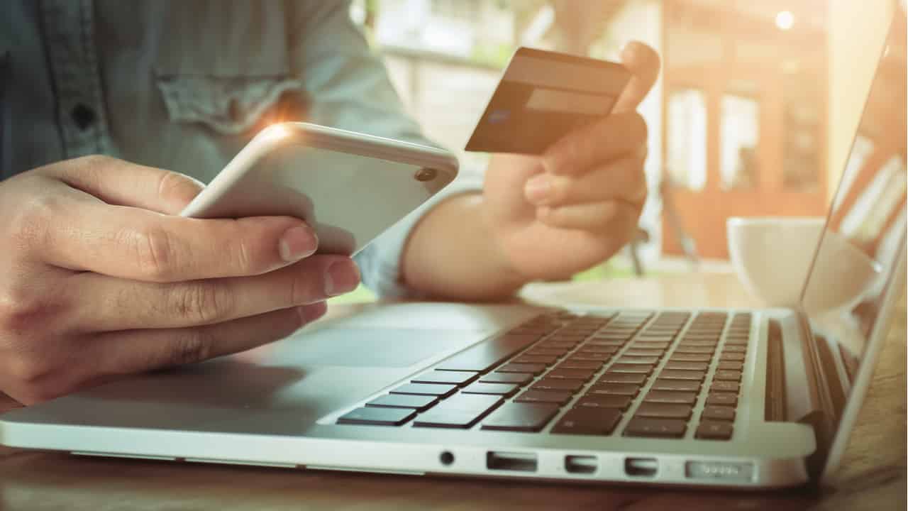 homem segura cartão de crédito enquanto olha para o celular