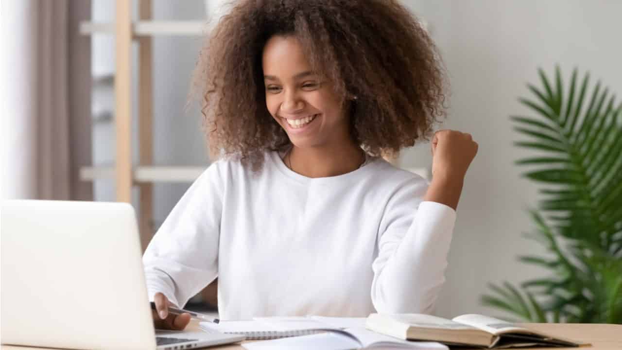 estudante sorri enquanto olha computador
