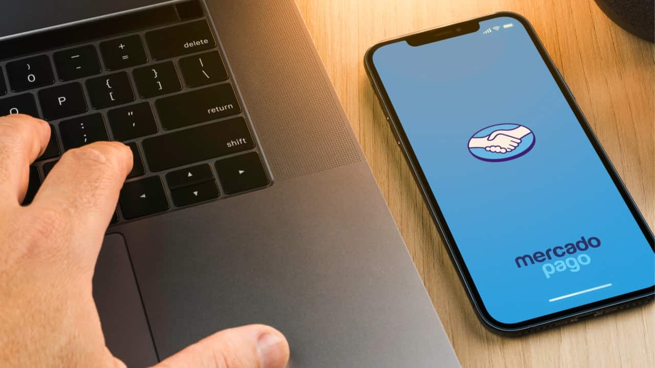 Celular mostrando o aplicativo Mercado Pago ao lado de um notebook