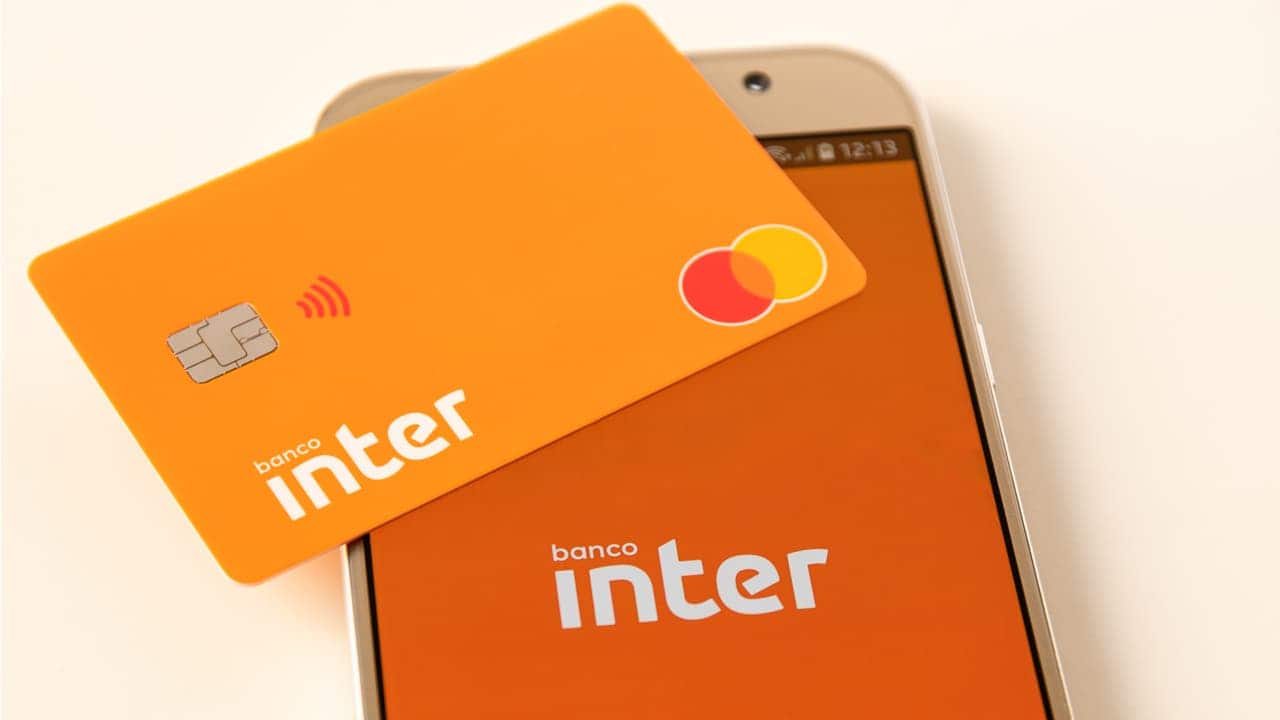 Cartão do banco Inter em cima de celular com o aplicativo do banco na tela