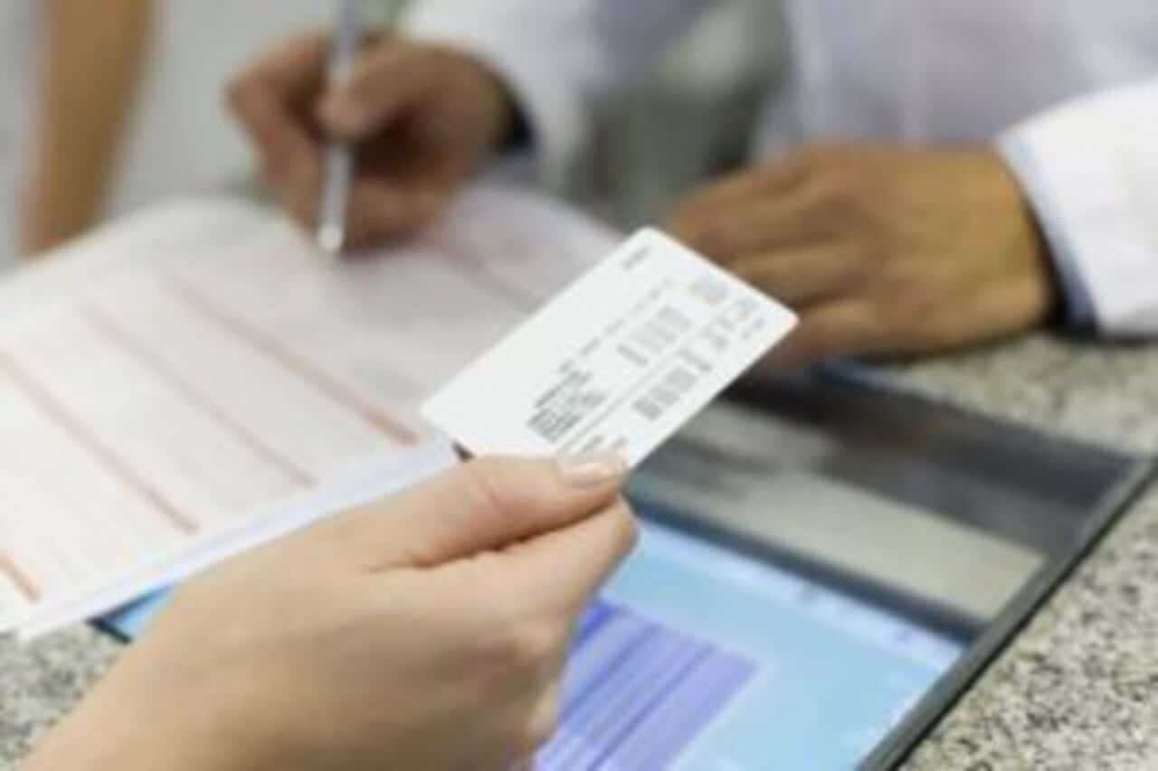 Mão segurando carteira de convênio planos de saúde