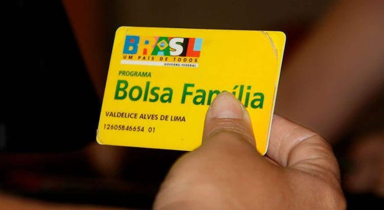 Mão segurando cartão do Bolsa Família