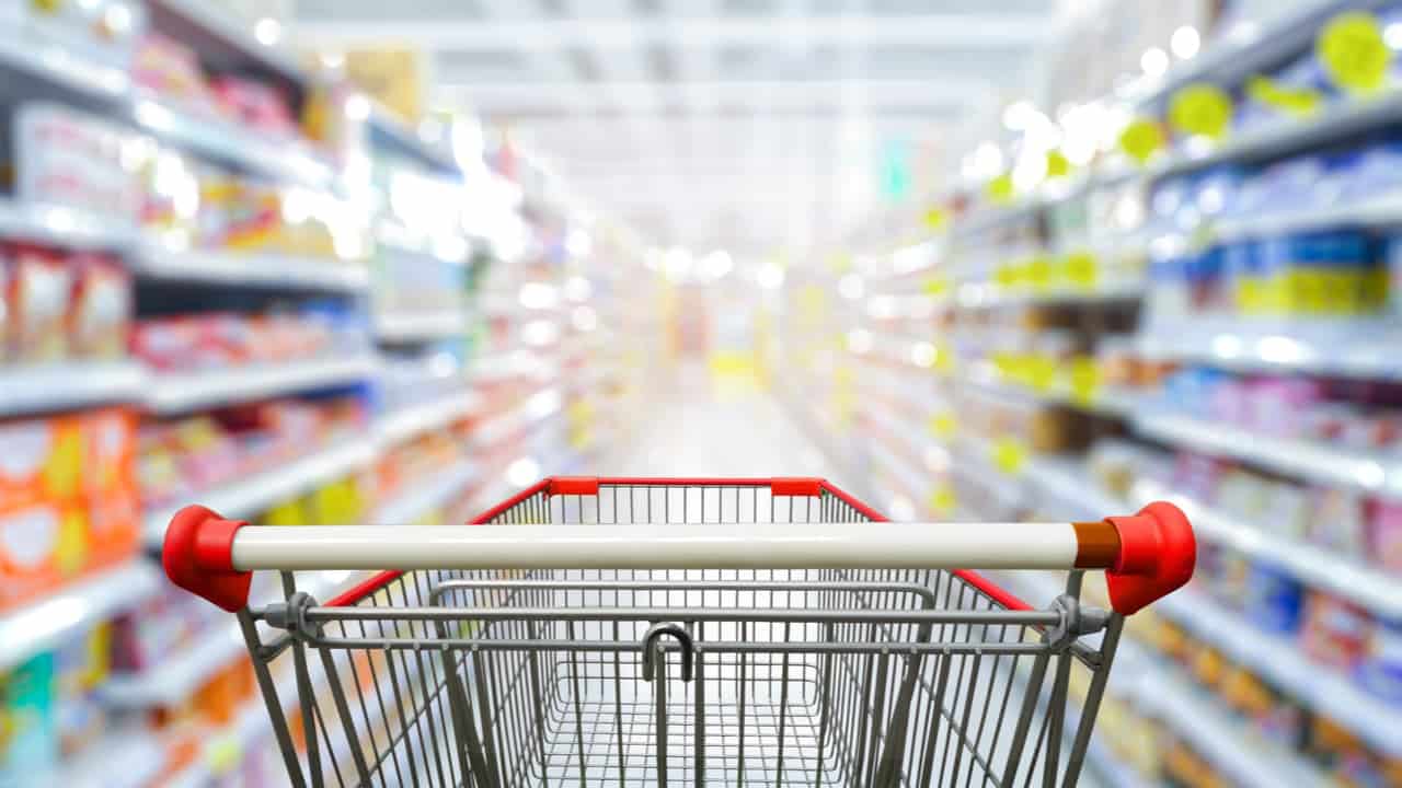 Carrinho de supermercado no centro entre duas fileiras de produtos