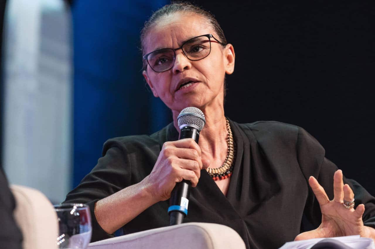 Marina Silva, ministra do Meio Ambiente, durante discurso, segurando um microfone.