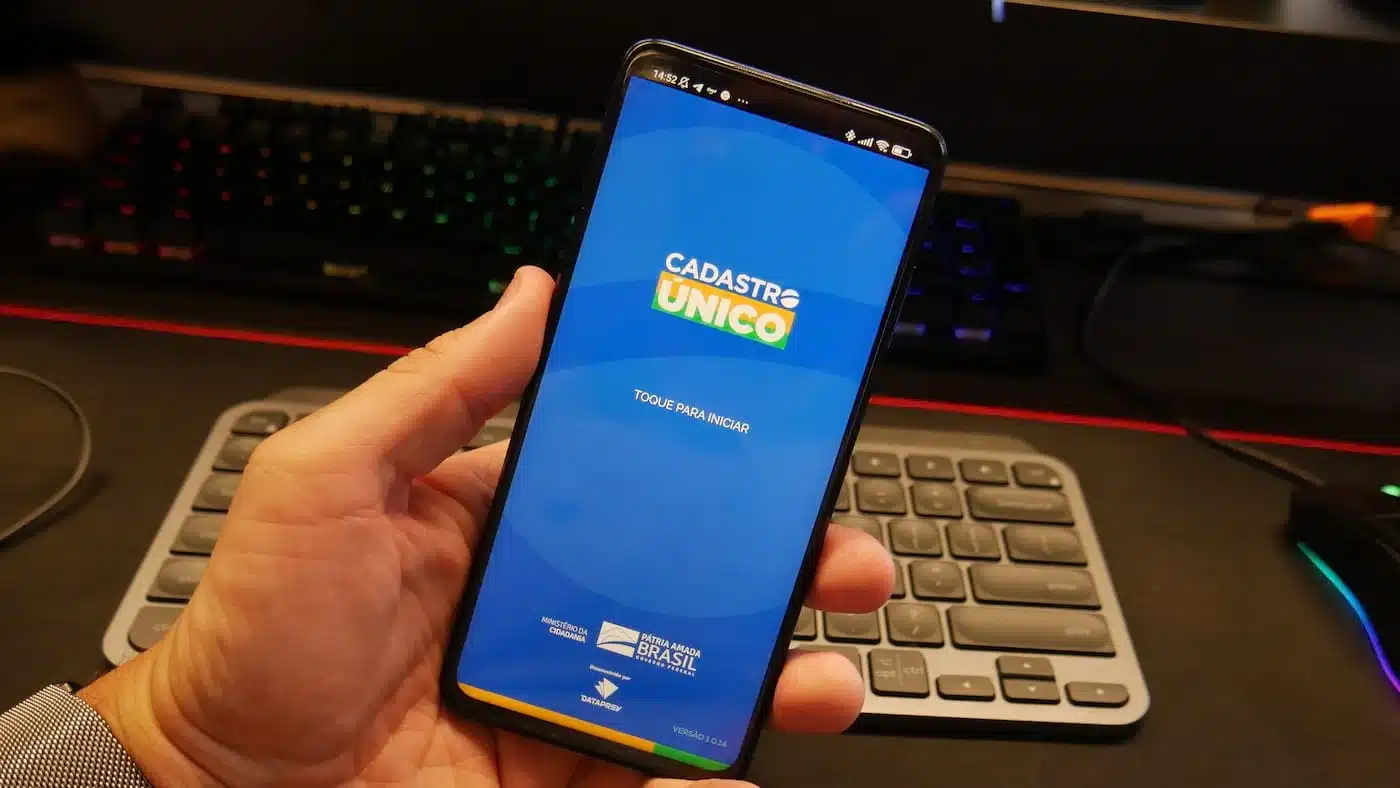 mão segura o celular com o app do governo, Cadastro Único, aberto