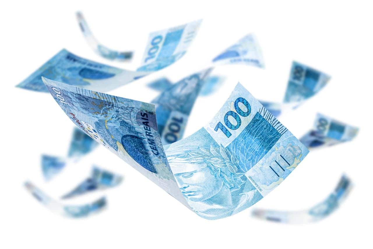 Notas de 100 reais flutuando no ar em fundo branco