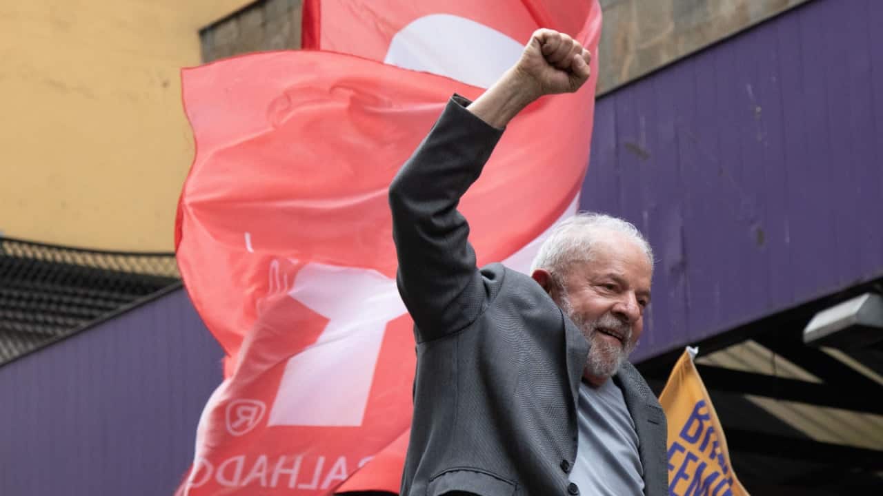 Presidente Lula em manifestação, com semblante alegre e erguendo seu punho fechado para cima