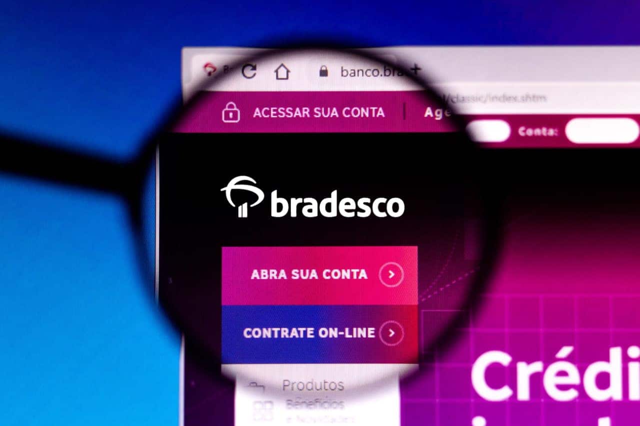 Tela mostrando site do banco Bradesco. Em primeiro plano, uma lupa aproxima a imagem do logo da instituição.
