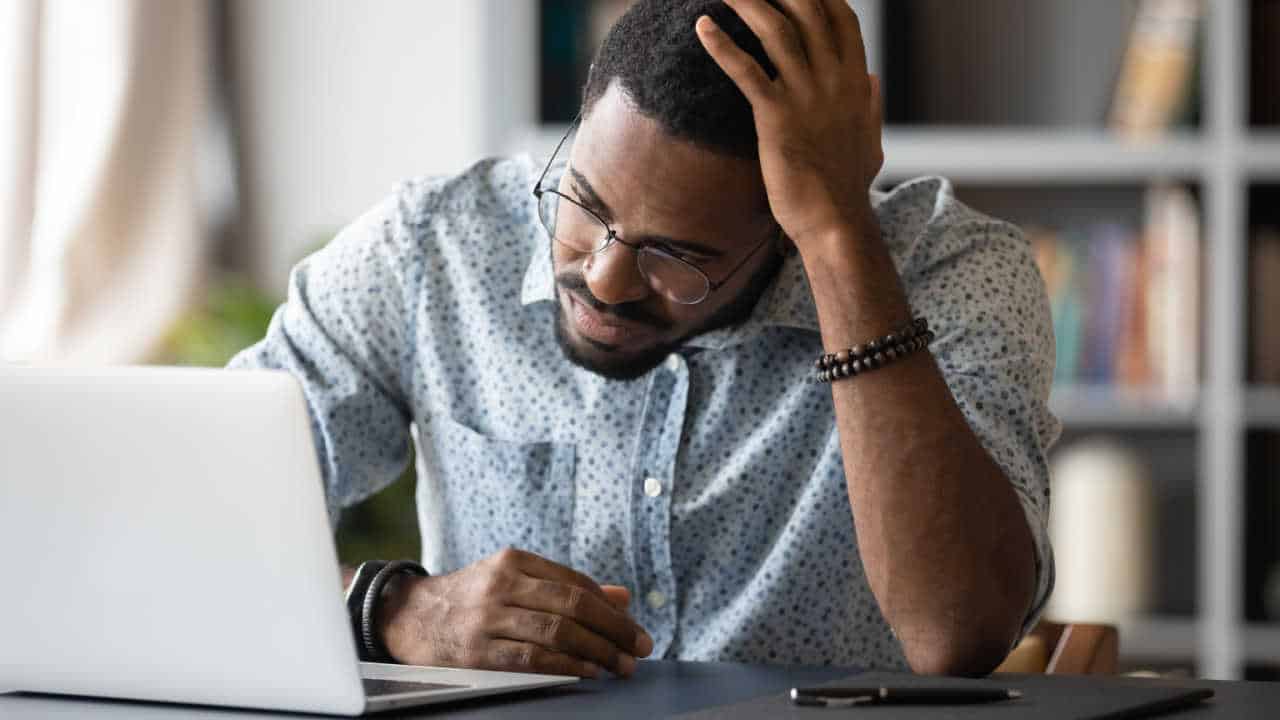 homem em frente ao notebook com expressão séria