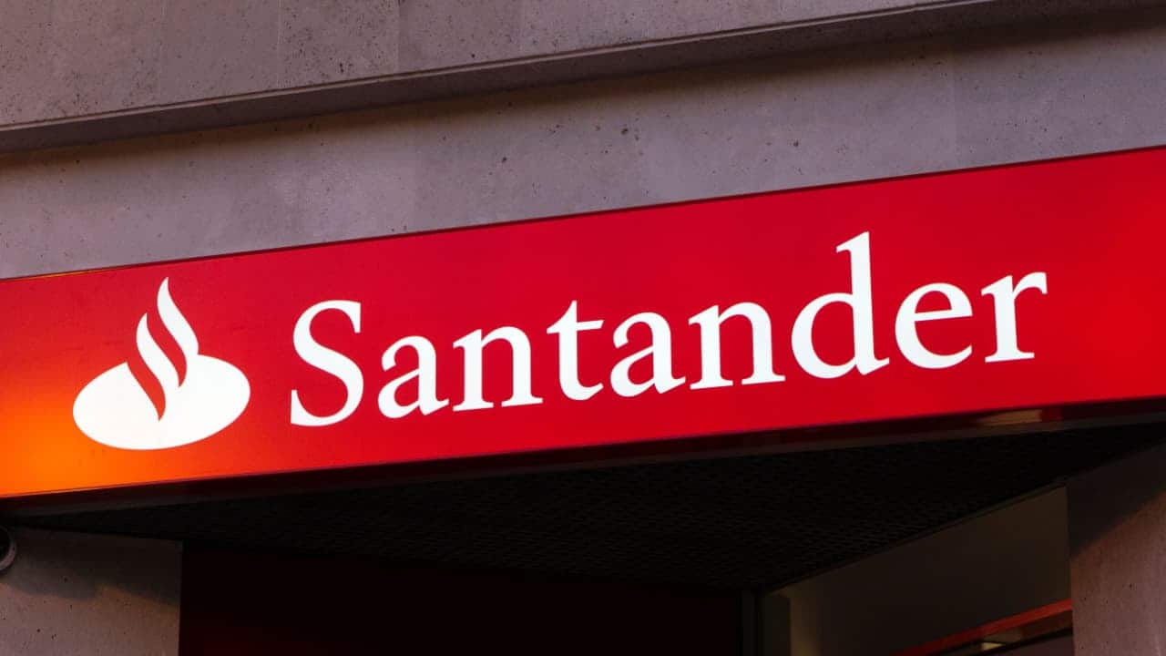 Fachada de unidade do banco Santander com o letreiro branco sobre a faixa vermelha