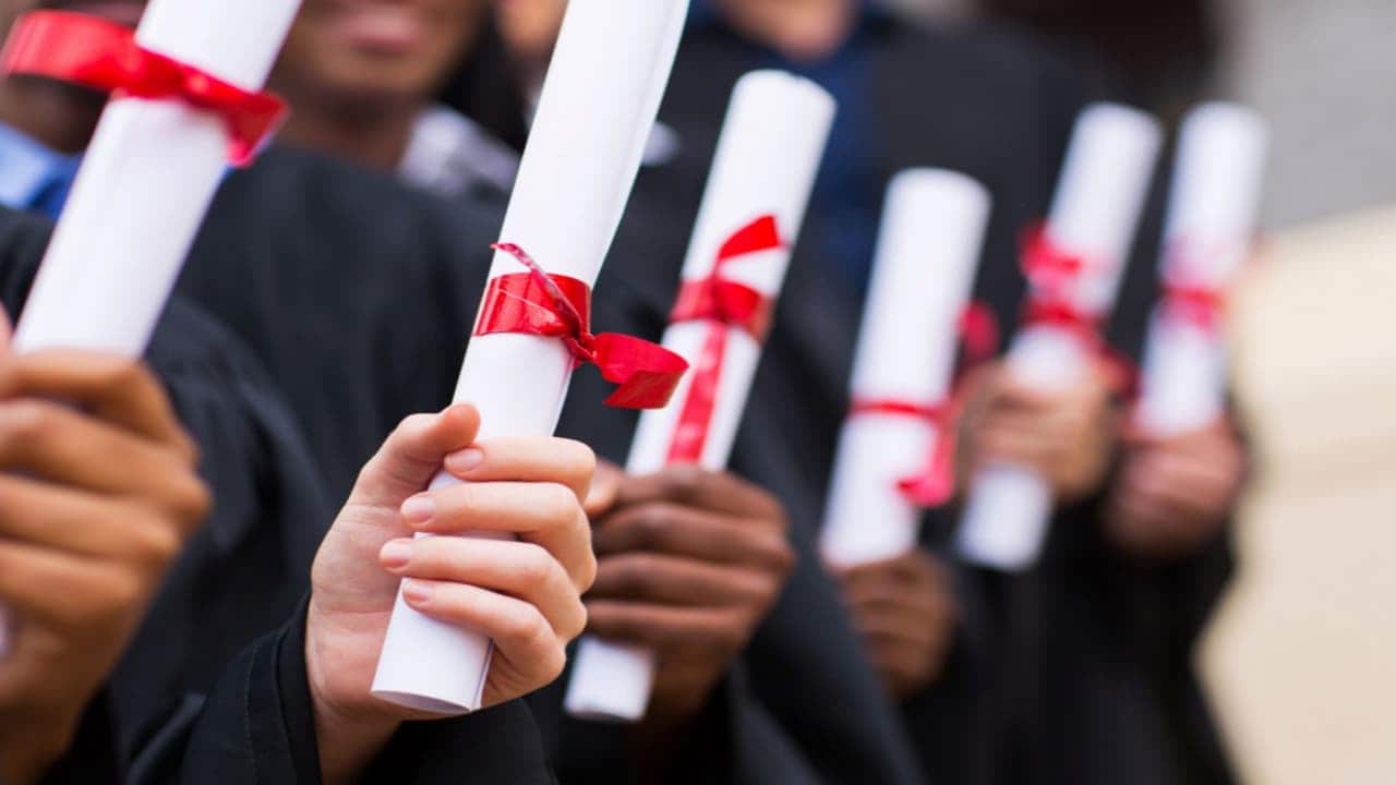 Universitários segurando diplomas
