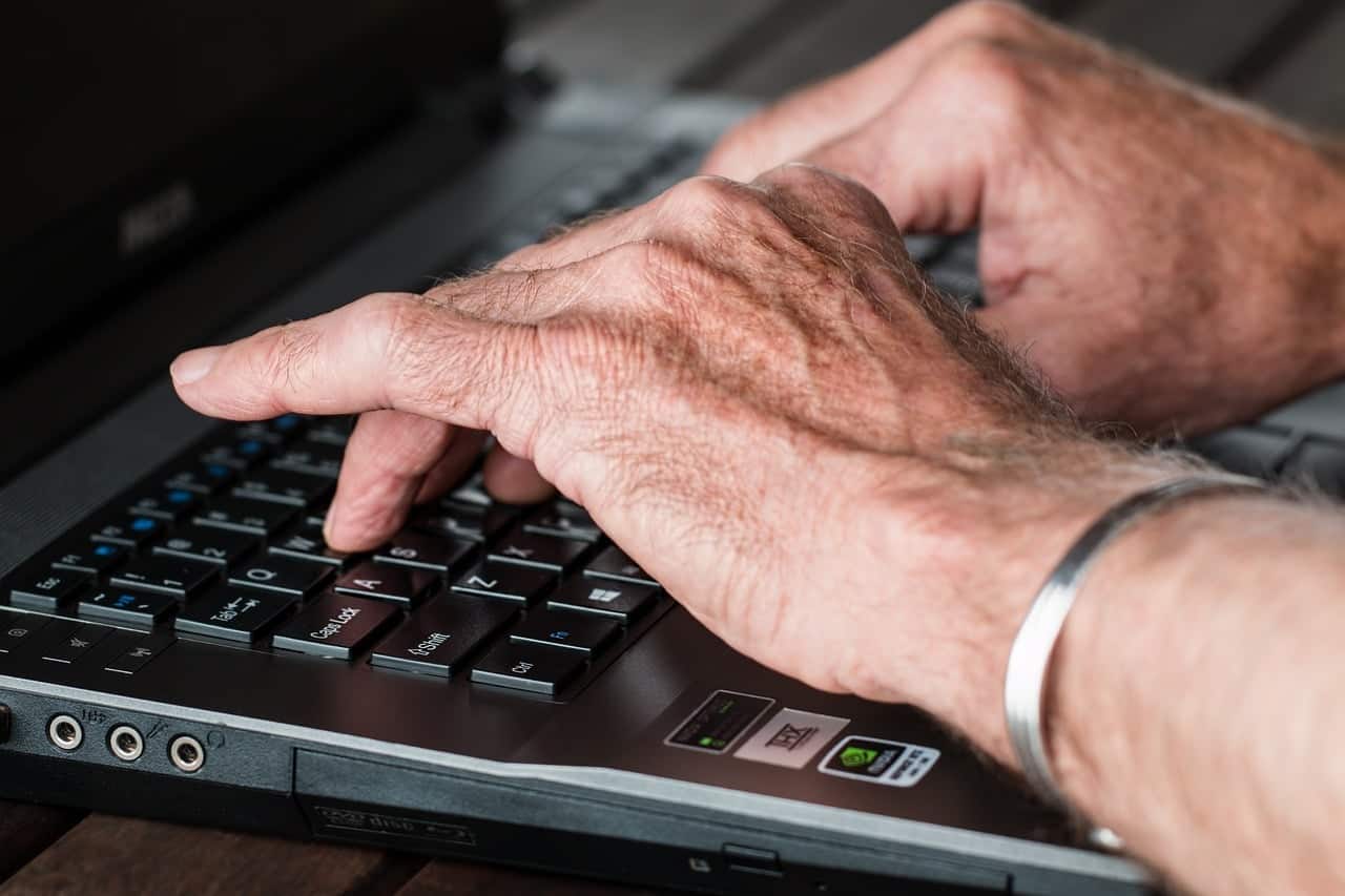 mão de pessoa idosa digitando em um teclado