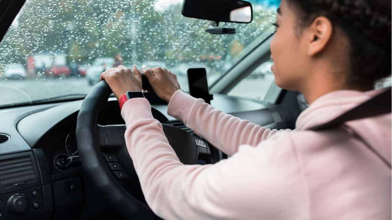 Foto de perfil de uma mulher com as mãos no volante