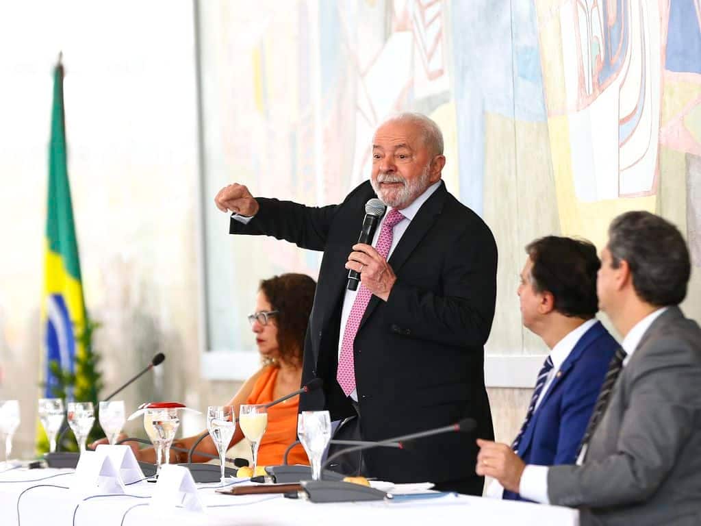 Lula fazendo um discurso de pé ao lado de outros executivos crédito