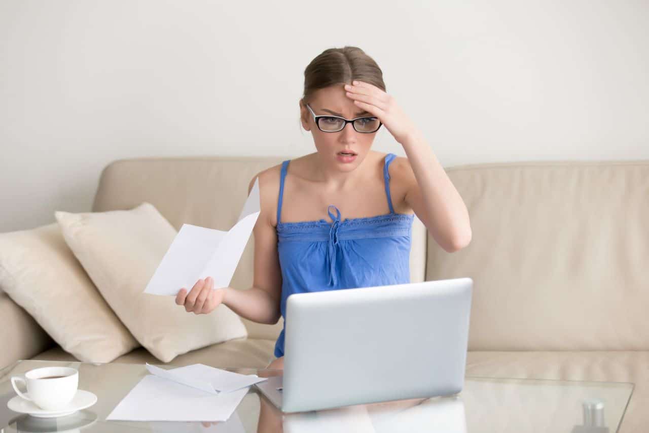 Mulher frustrada com mão na cabeça vendo o notebook