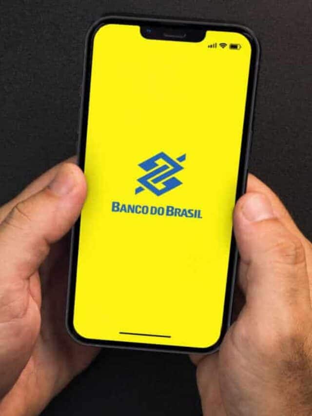 Aparelho celular segurado com duas mãos com o aplicativo do Banco do Brasil aberto na tela inicial