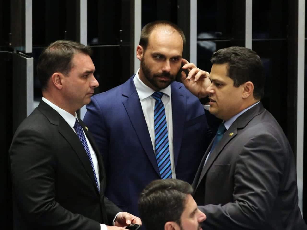 Imagem de conversa entre Flávio Bolsonaro, Carlos Bolsonaro e Davi Alcolumbre no plenário.