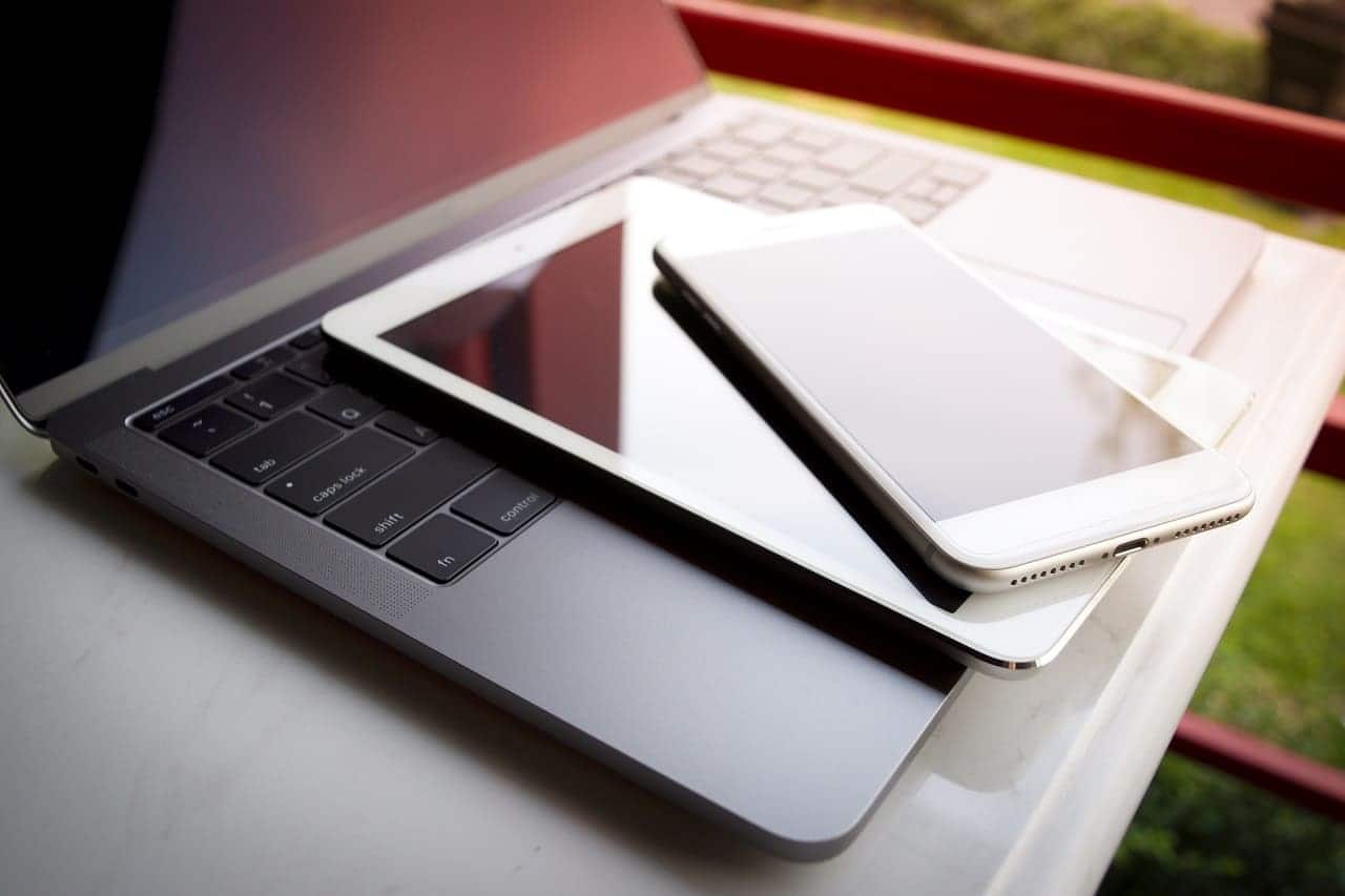 Imagem mostra um celular em cima de um tablet, que por sua vez, está em cima do teclado de um notebook para entrar em sites.