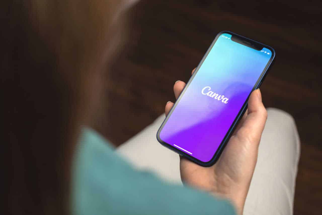 Mão segurando celular com app Canva aberto