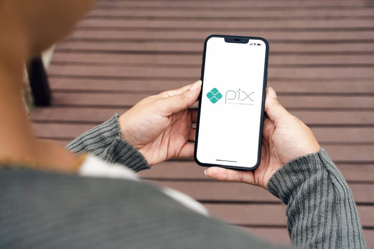 Mão segurando celular com logo do Pix aberto