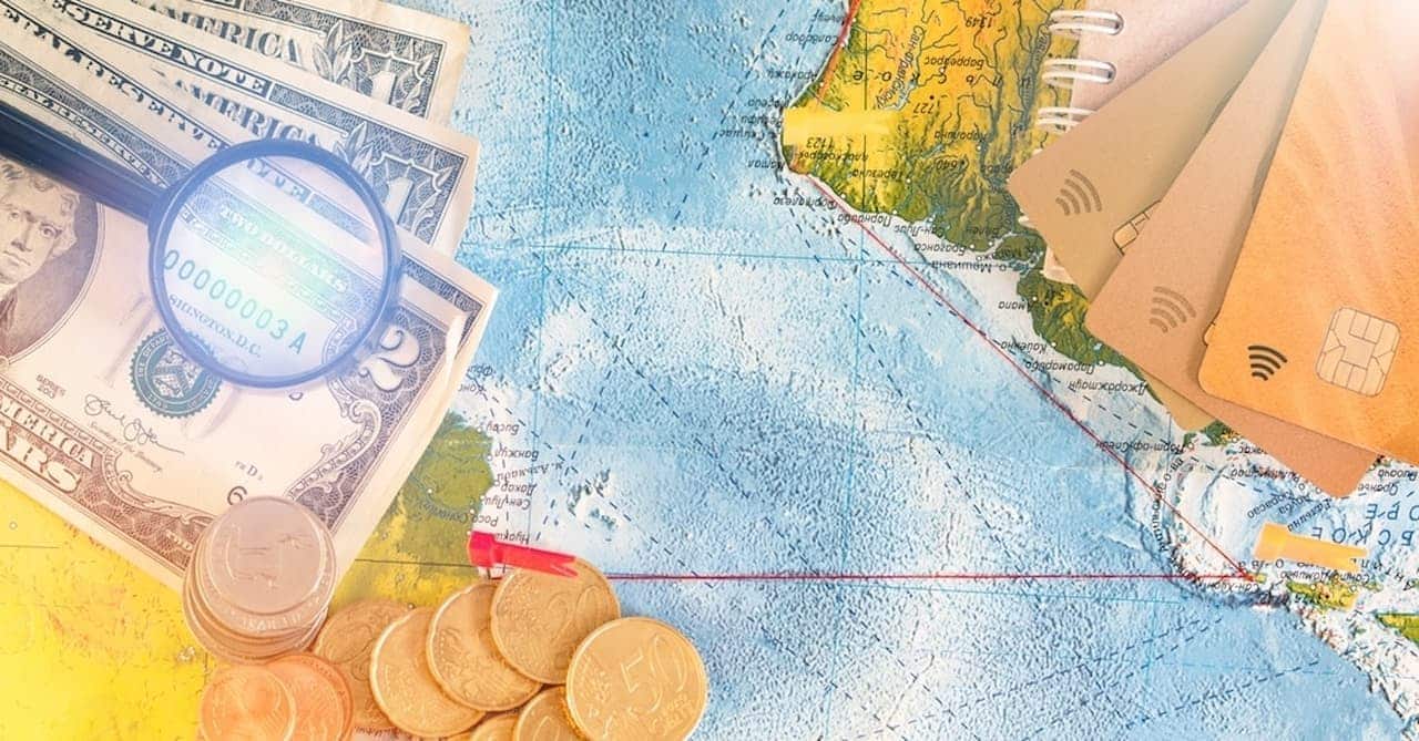 Imagem de moedas, notas e cartões sobre um mapa