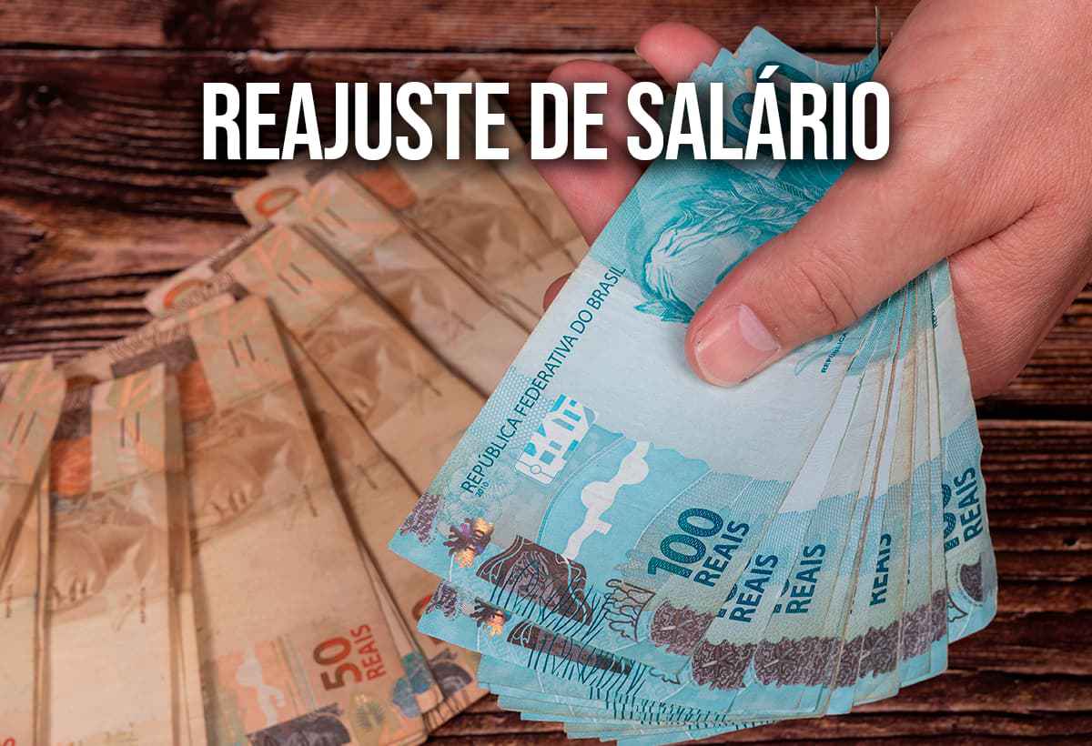 Mãos segurando notas de real com o escrito "reajuste de salário"