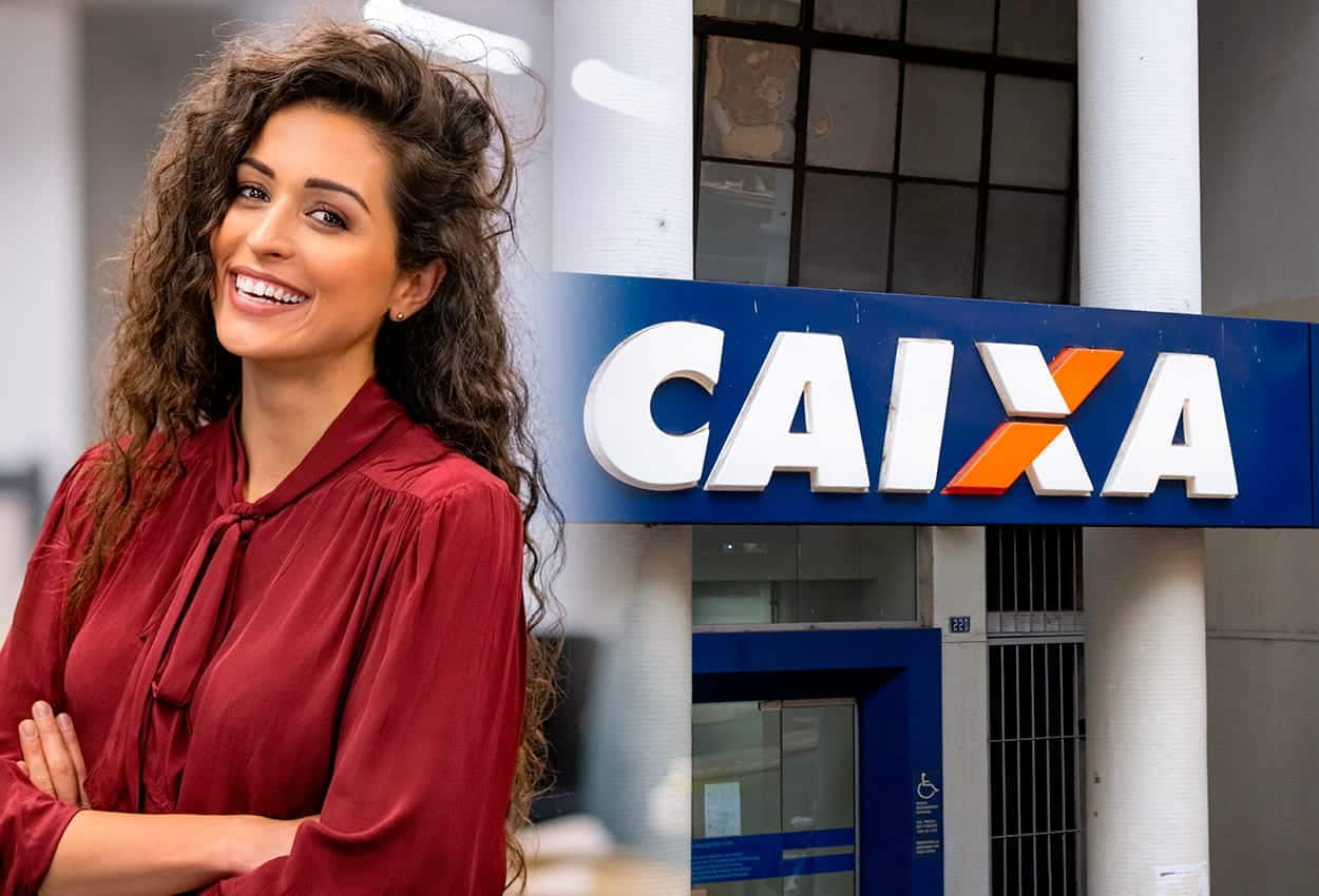 Imagem de uma mulher sorrindo com os braços cruzados, ela está na frente de uma agência da Caixa Econômica Federal.
