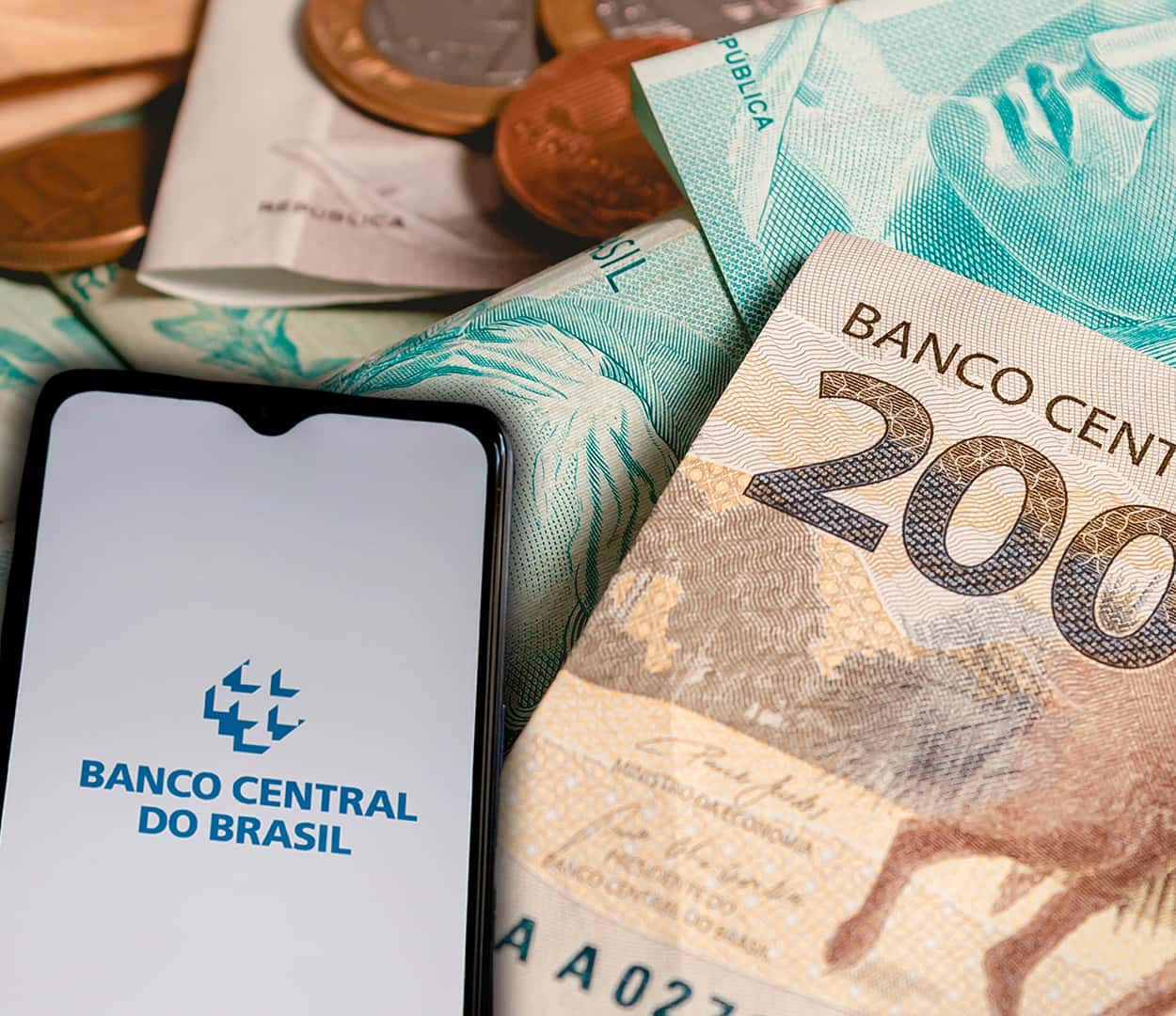 Celular com app do Banco Central na tela ao lado de notas de real