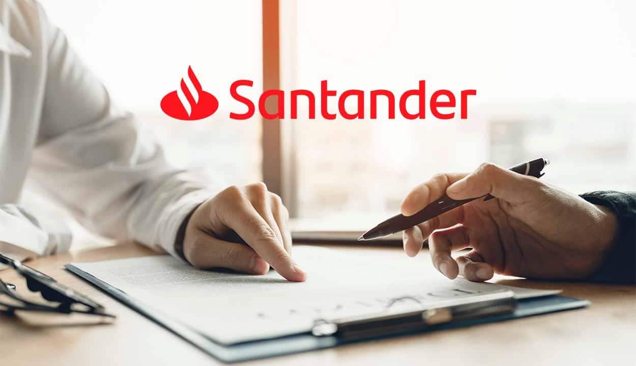 Mãos de duas pessoas, uma aponta para documento e outra segura uma caneta para assinar. Logo do Santander centralizada