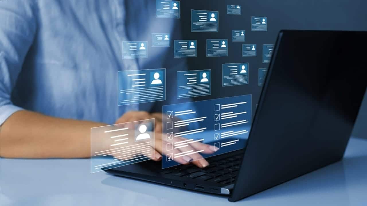 Imagem de uma pessoa digitando em um computador. Acima das teclas, ilustrações de dados digitais.