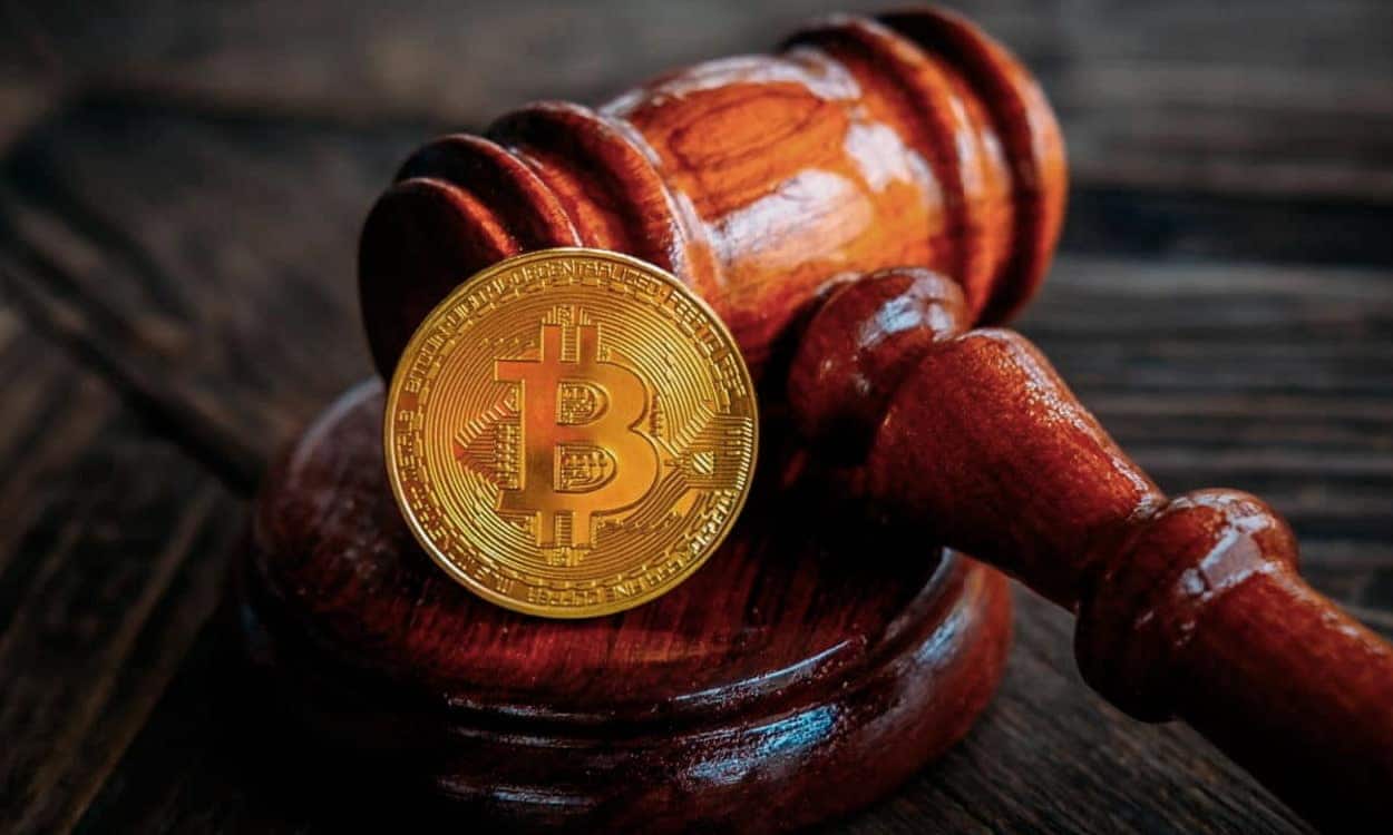 Martelo de juiz com uma moeda de bitcoin apoiada sobre ele