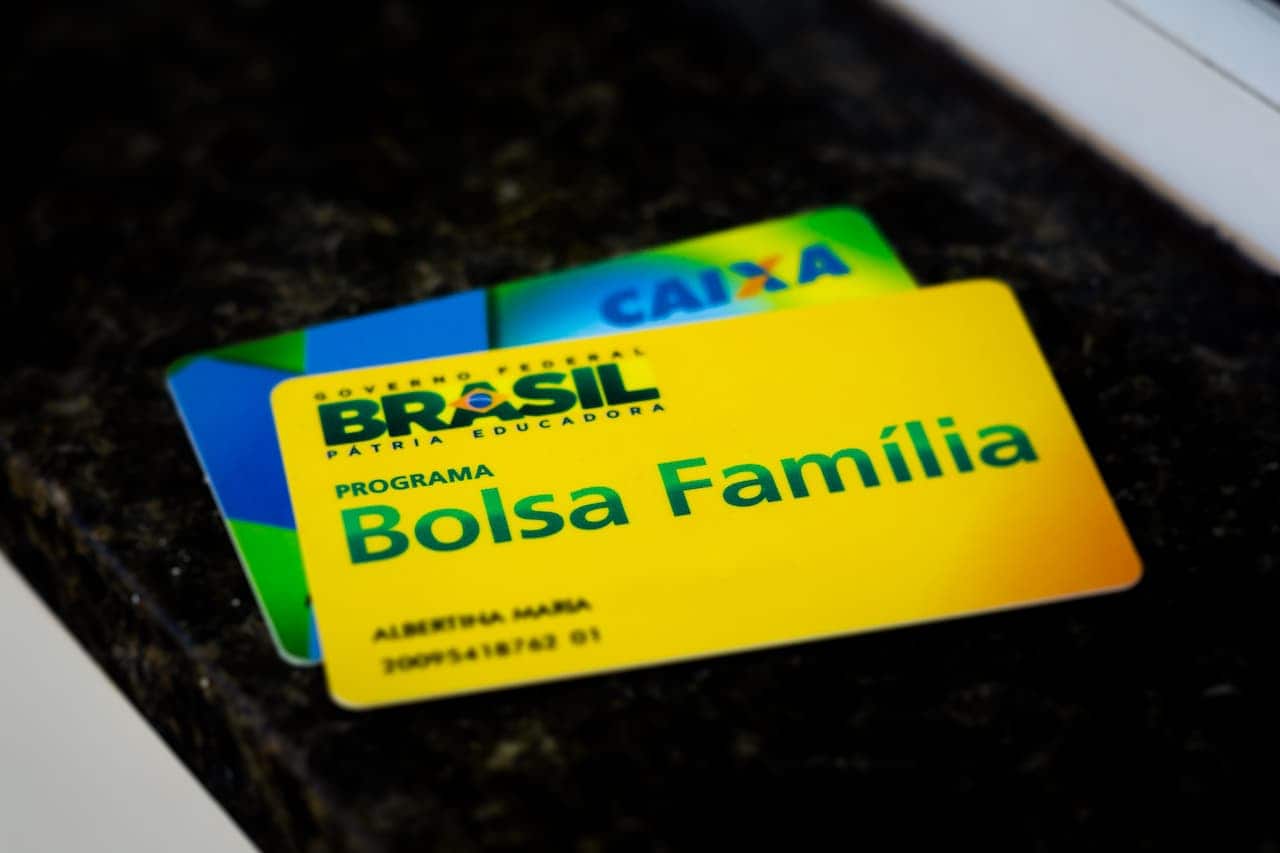 cartão do Bolsa Família em cima de cartão da Caixa em fundo preto