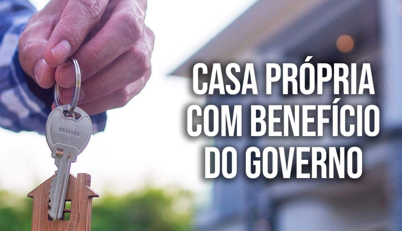 mão masculina segurando chave da casa ao fundo, ao lado dele a frase escrita "casa própria com beneficio do governo".