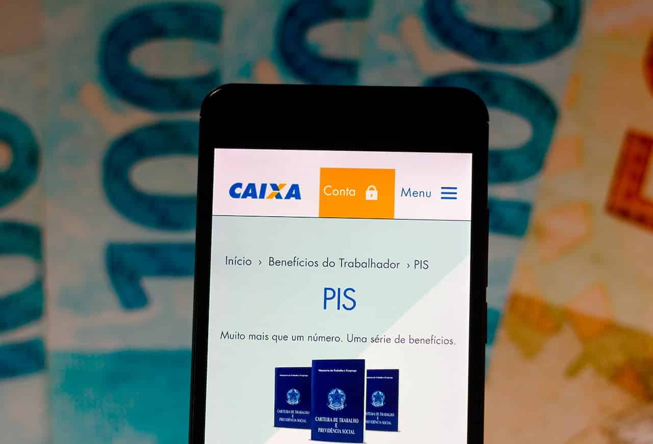 Celular mostrando a página do programa PIS no aplicativo da Caixa. Ao fundo, notas de dinheiro.