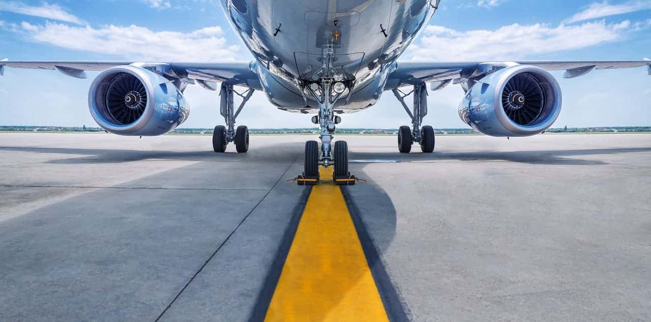 Imagem da parte inferior de um avião que está pousado em pista de voo.