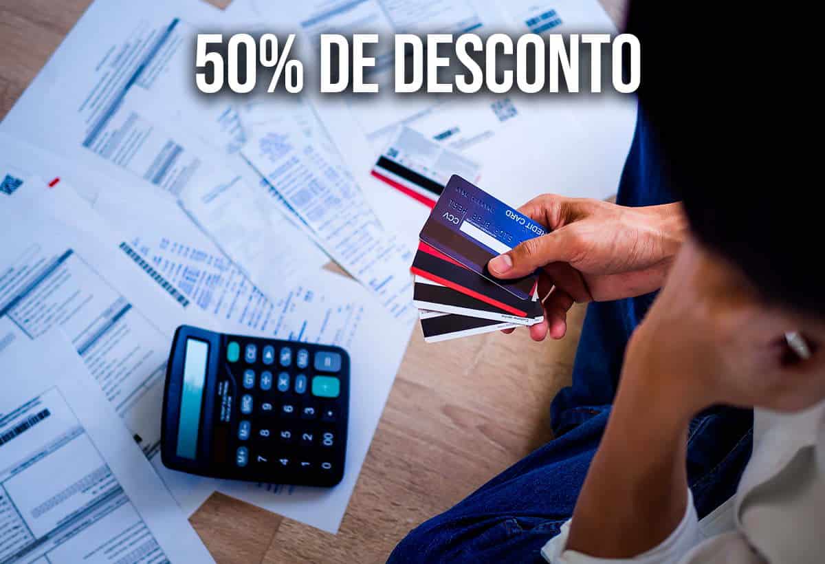Imagem de uma pessoa segurando cartões enquanto olha para boletos e calculadora. Além do texto "50% de desconto".