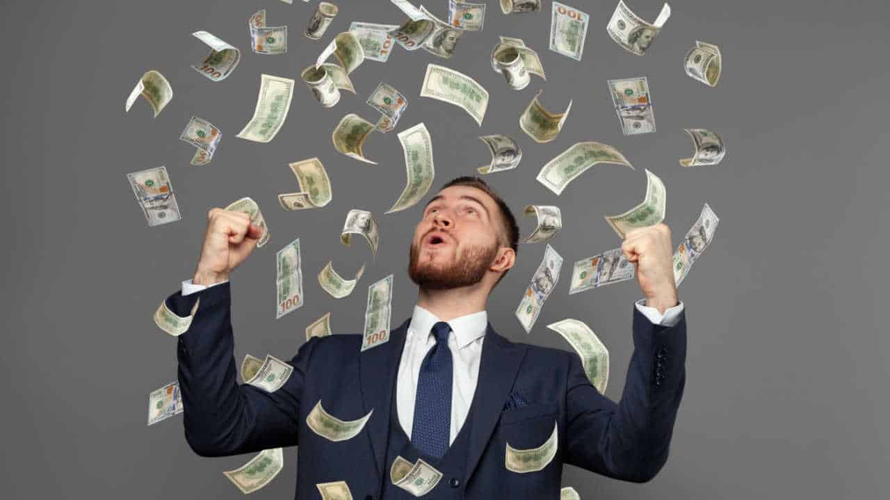 gestor de TI comemorando com os punhos para cima, enquanto caiem notas de dinheiro do céu - Carreiras