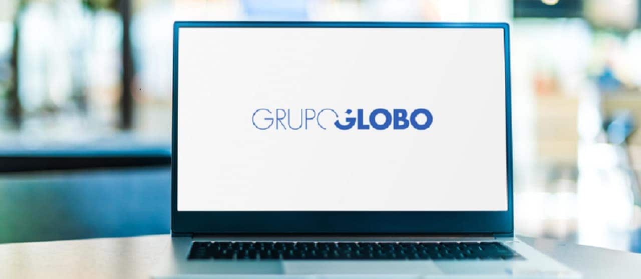 Imagem de um computador sobre uma mesa. Na tela está o logo do Grupo Globo de televisão