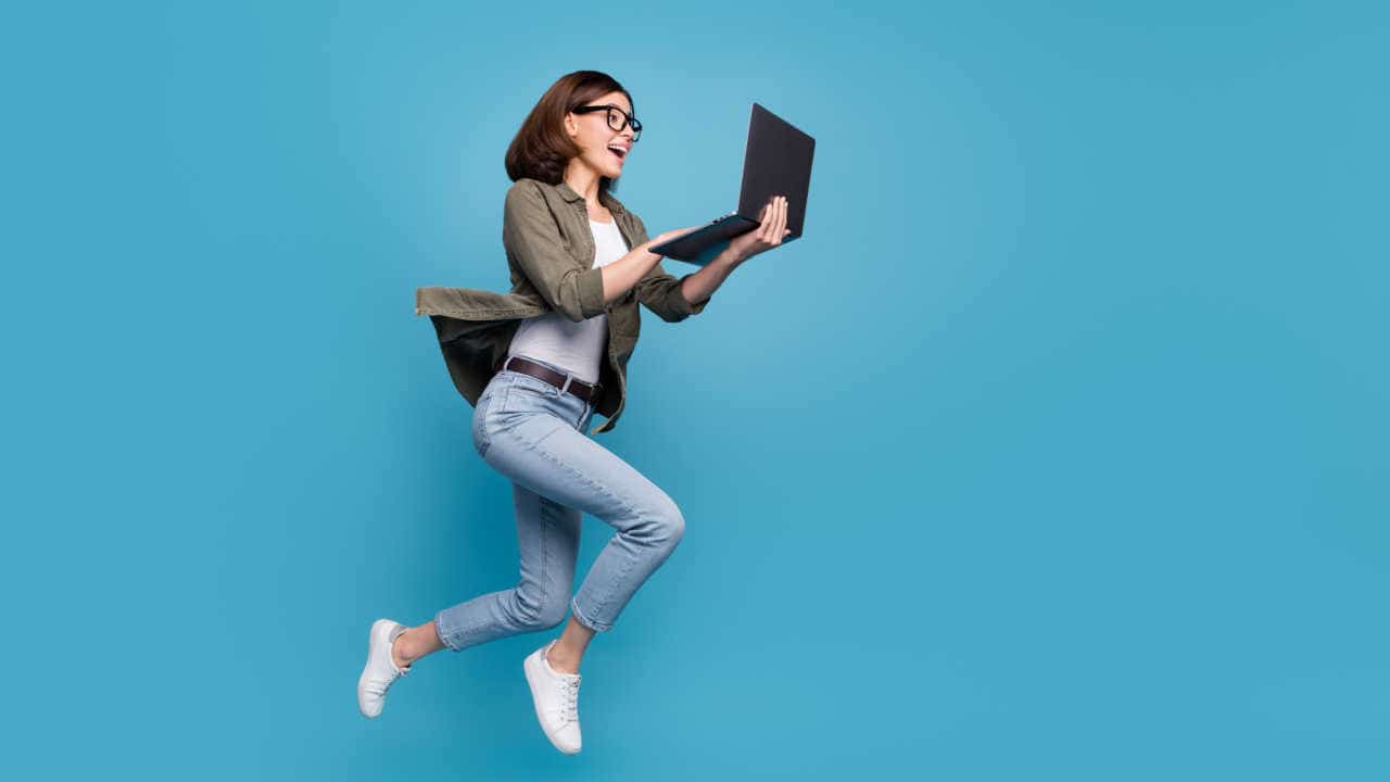mulher pulando para outra direção com um notebook na mão