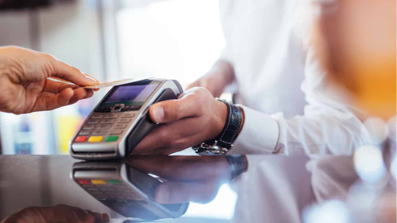 Mãos segurando maquininha de cartão para pagamento