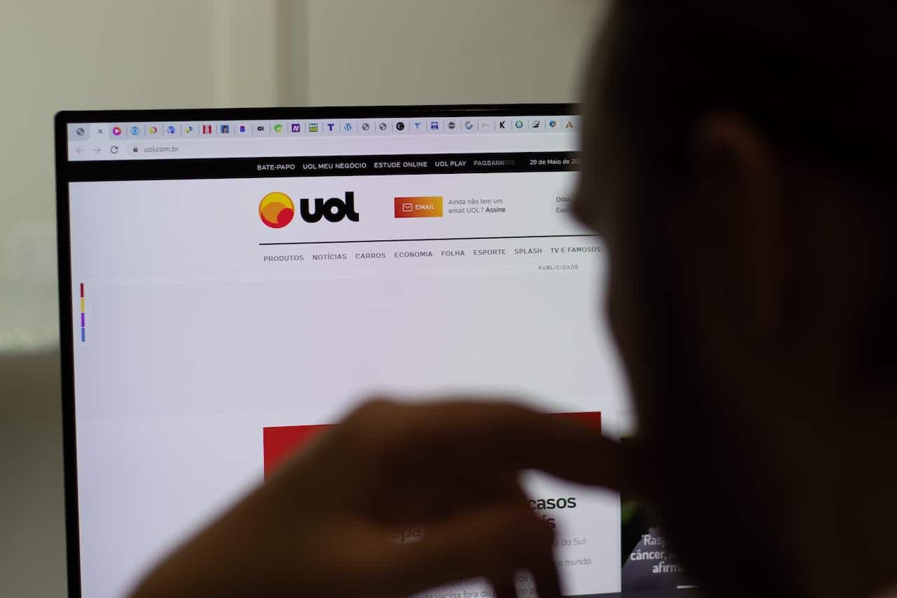 Pessoa em frente a um notebook com o site da Uol aberto