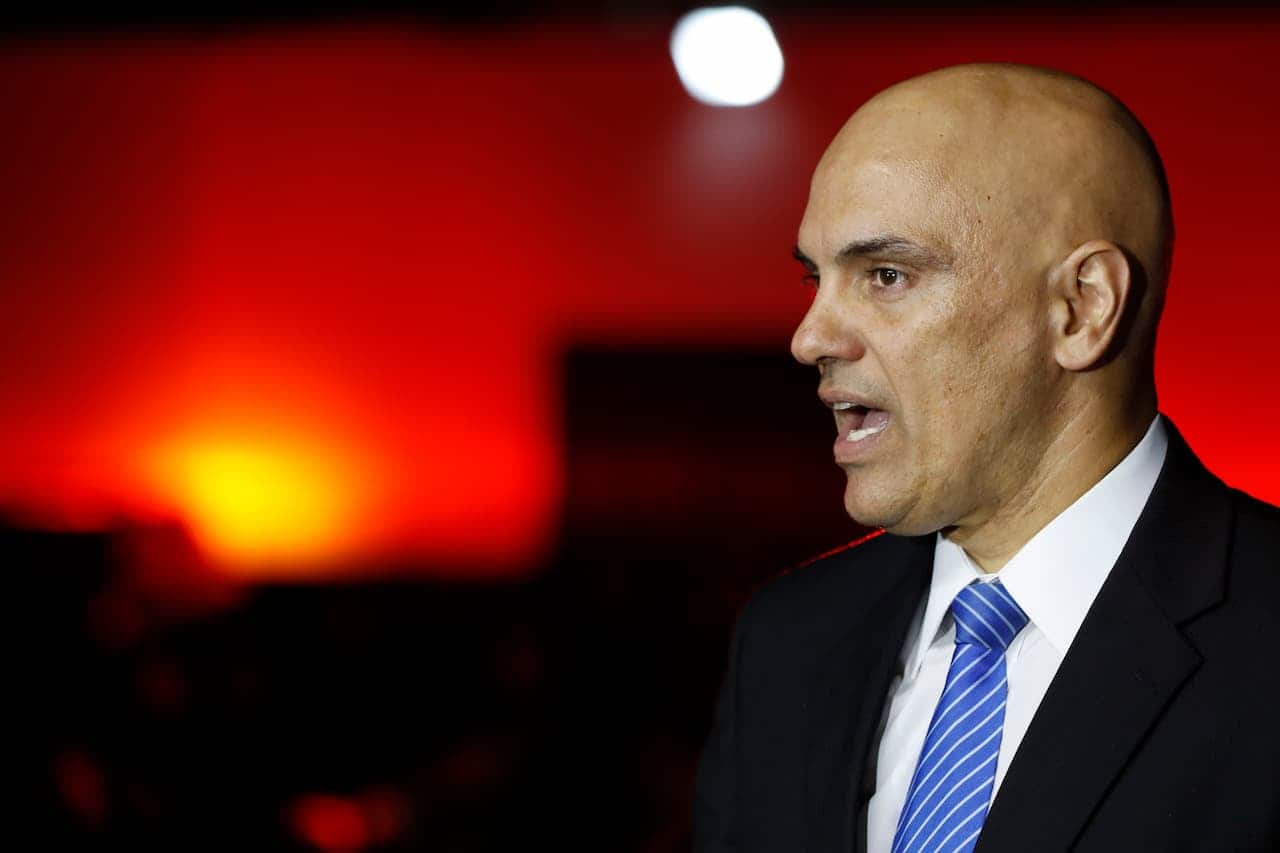 Ministro do STF Alexandre de Moraes de perfil, com a boca entreaberta, durante uma fala. Lei Magnitsky