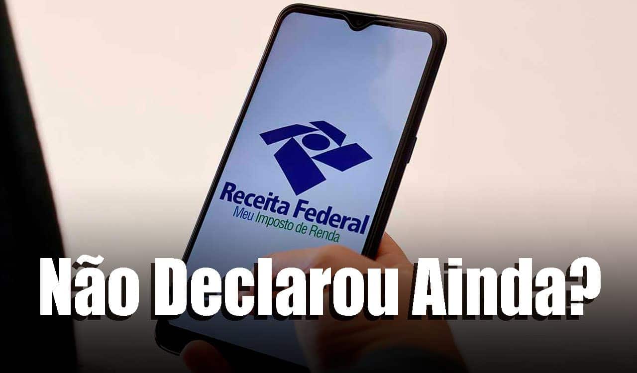 Uma mão segura celular que mostra o app do Meu Imposto de Renda ao fundo. Em destaque a frase: Não declarou ainda? escrita em tamanho maior e em letras brancas.