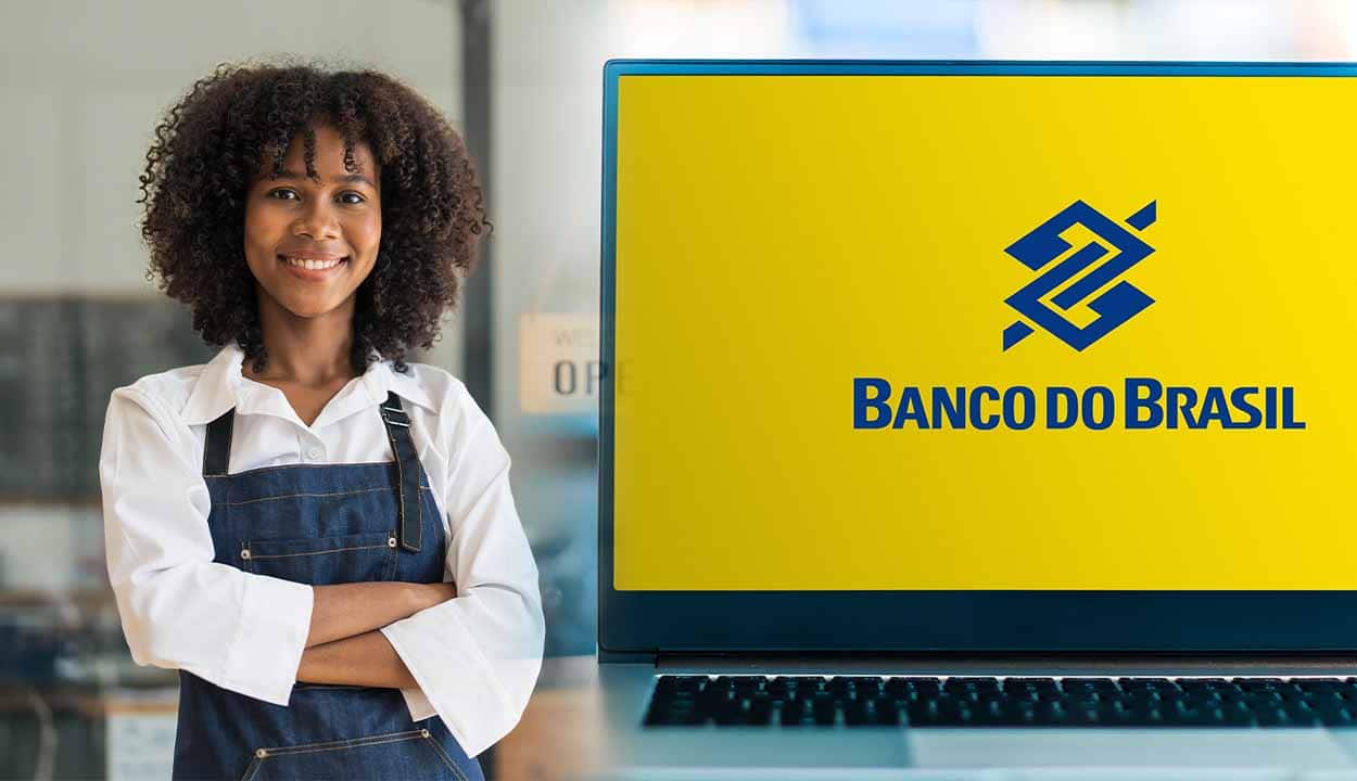 mulher negra de roupa profissional e de braços cruzados ao lado de uma tela com a logo do banco do brasil.
