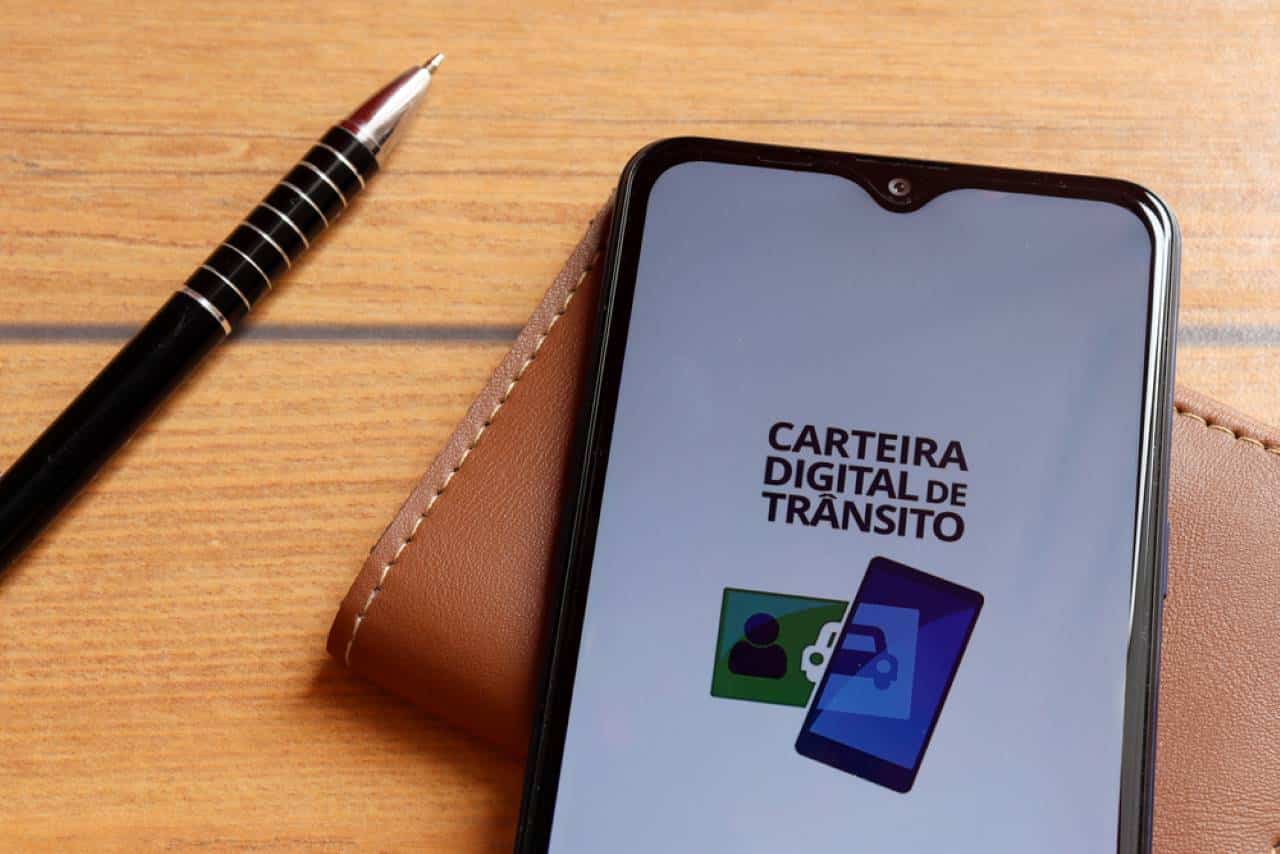 celular em cima de uma carteira e ao lado de uma caneta exibindo o aplicativo da CNH digital o Carteira Digital de Transito