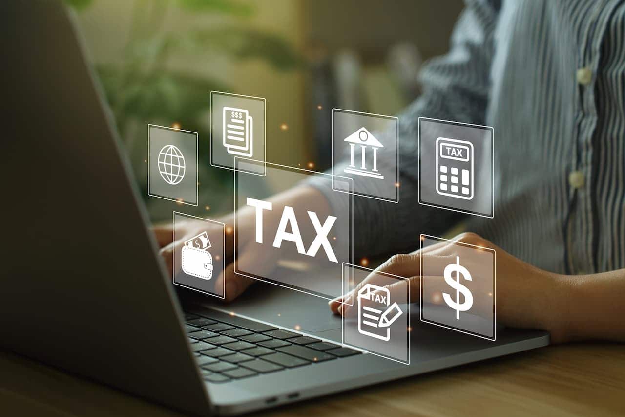 mãos digitando em laptop e vetores simbolizando taxas e impostos