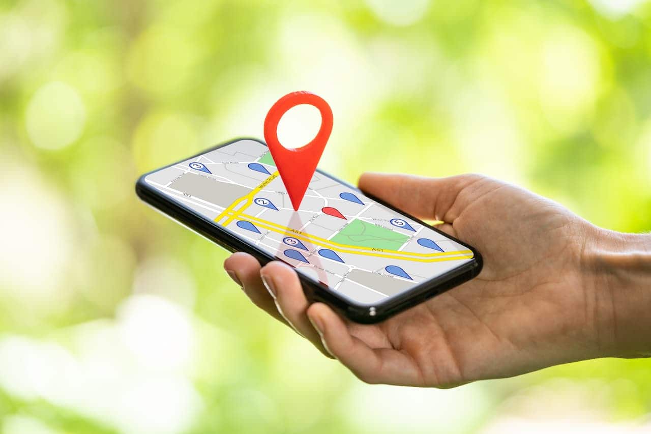 Mão segurando celular que exibe tela de um aplicativo de GPS