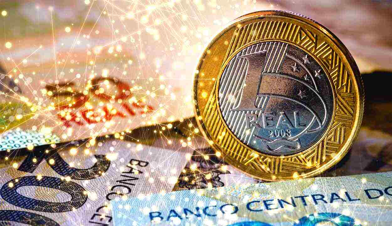 Moeda de R$ 1 com cédulas ao fundo. Sobre a imagem, há brilhos que remetem a símbolos tecnológicos