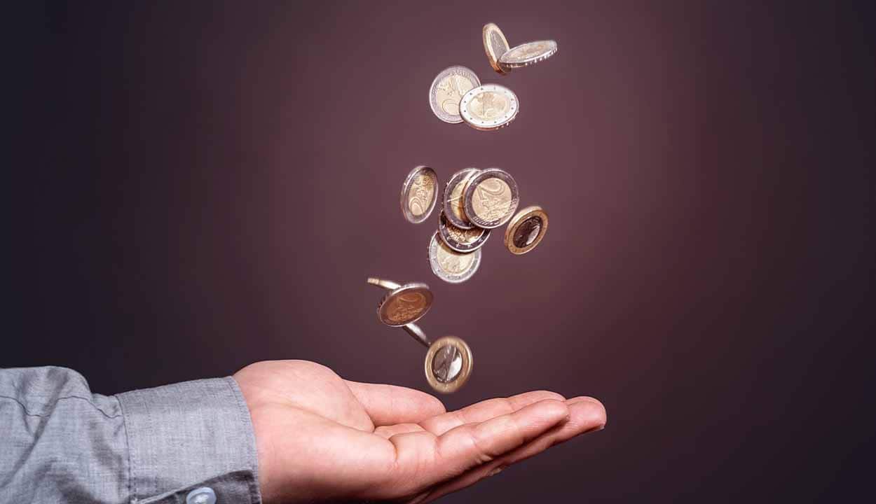 Moedas caindo em cima da palma da mão de uma pessoa