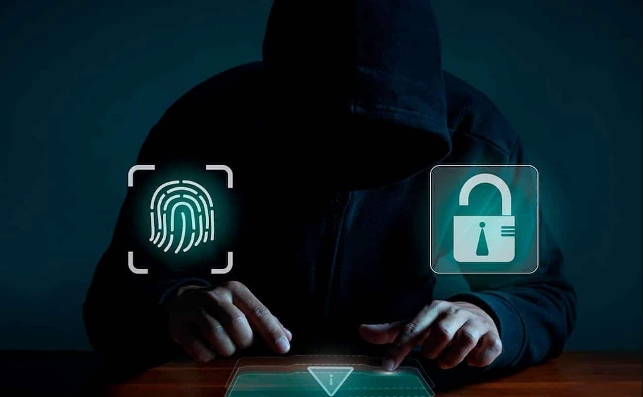 pessoa encapuzada usando um teclado. símbolos luminosos de uma digital e um cadeado aberto.